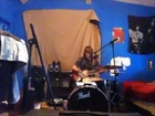 A young boy playing guitar and drums and singing at the same time